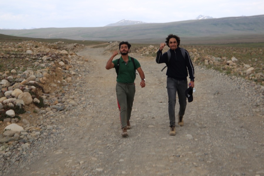 Talha hiking with a friend on a gravel trail, both smiling