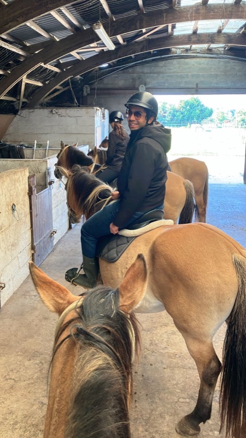 Talha horse riding, seated on a horse inside a stable