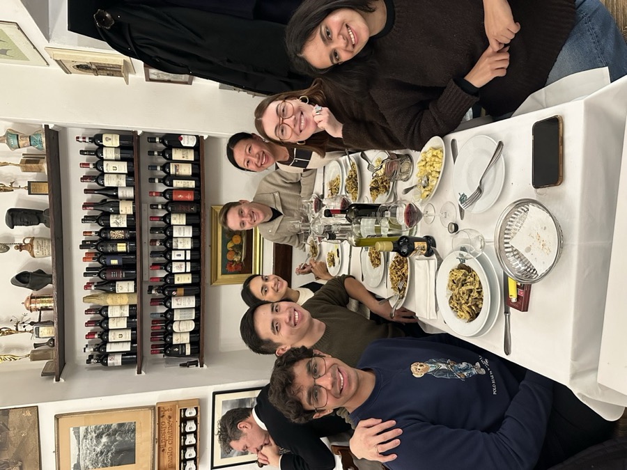 Talha at a group dinner with friends surrounded by wine bottles